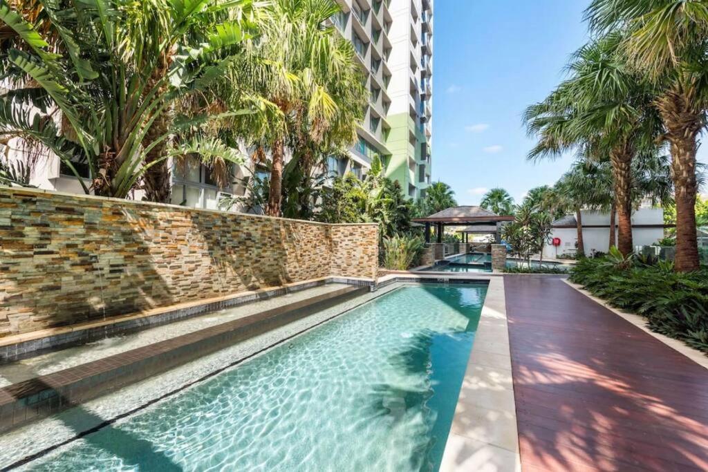 a swimming pool in front of a building with palm trees at Lovely 2 Bedroom unit Pool,Gym workspace & more in Brisbane