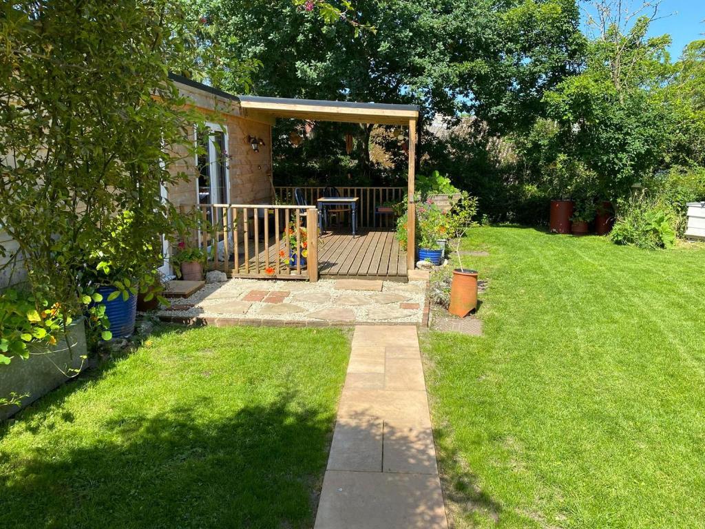 a backyard with a wooden deck and a playground at Beekeepers Cabin in Reepham