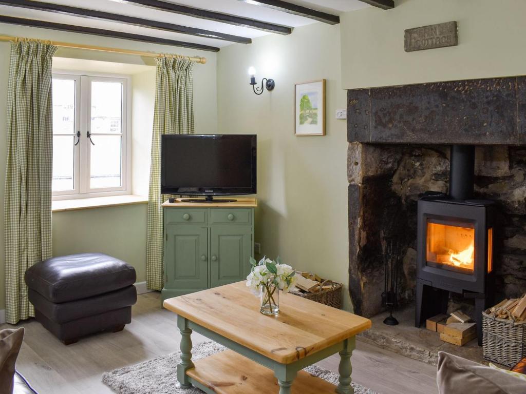 a living room with a fireplace and a tv at Fern Cottage in Bradwell