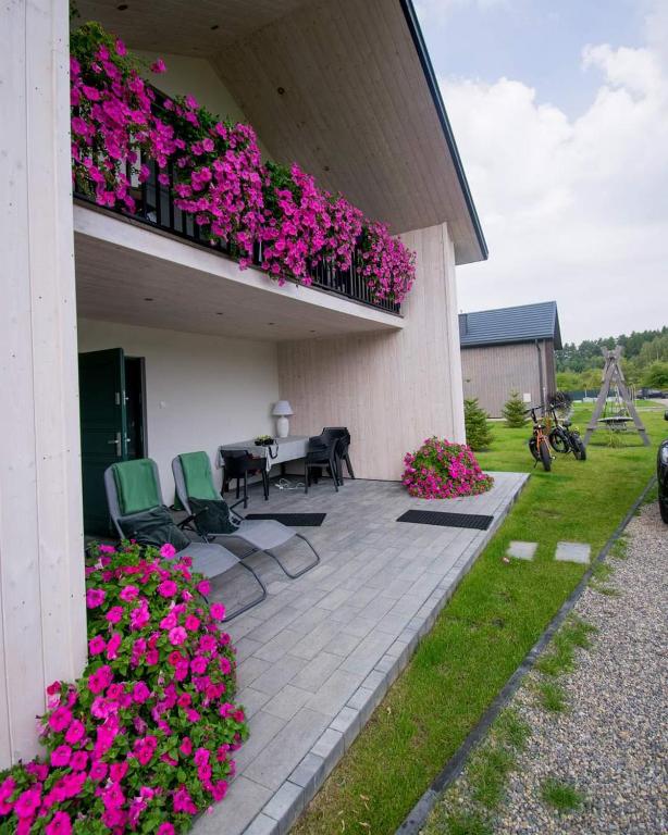 a patio with chairs and flowers on a building at Krzaczasty Zakątek in Zdziary