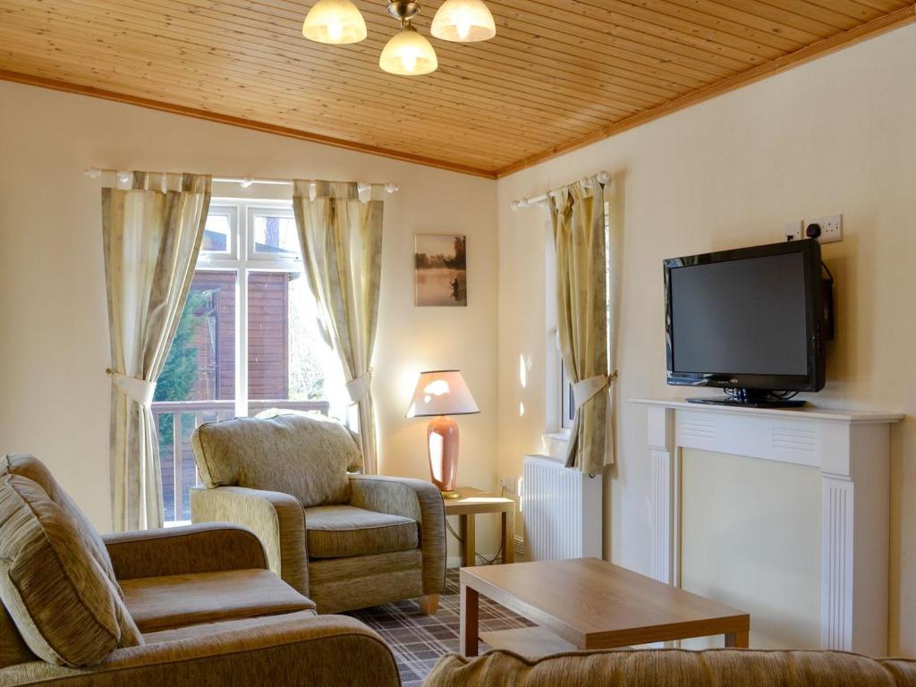 a living room with a tv and chairs and a fireplace at Lodge C- Uk33089 in Dinnet