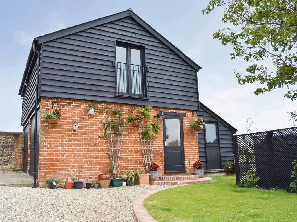 a brick house with a black roof at Pilgrims Barn in Hitcham
