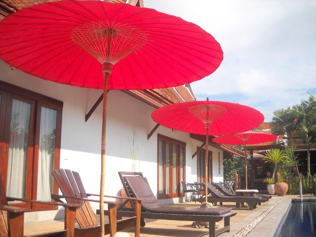 a group of red umbrellas sitting on a patio at Sea Pines & Liberg in Nai Yang Beach