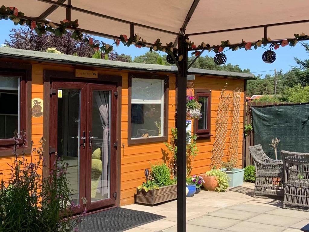 una casa arancione con patio e ombrellone di Bumbles Barn a Slamannan
