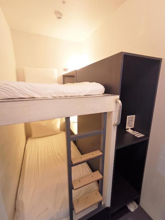 a bunk bed in a small room with a ladder at Inn Cube - Ximen in Taipei