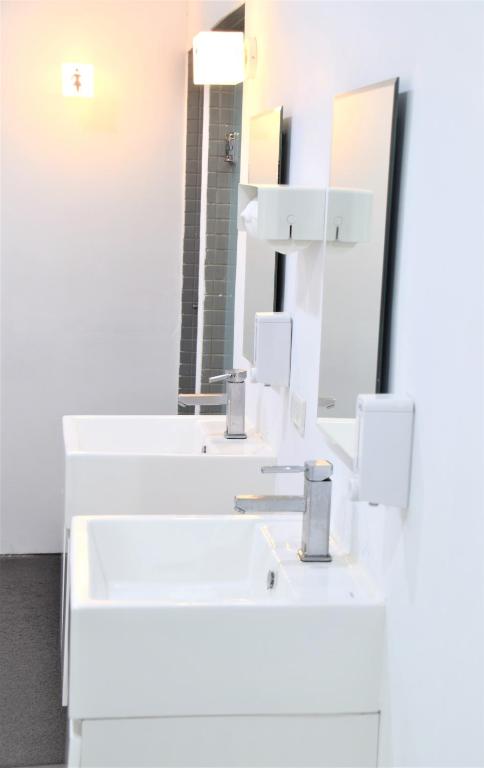 a white bathroom with two sinks and a mirror at Inn Cube - Ximen in Taipei