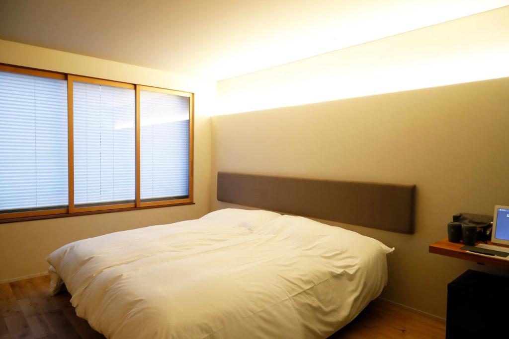 a bedroom with a white bed and two windows at Matsumoto Jujo in Matsumoto