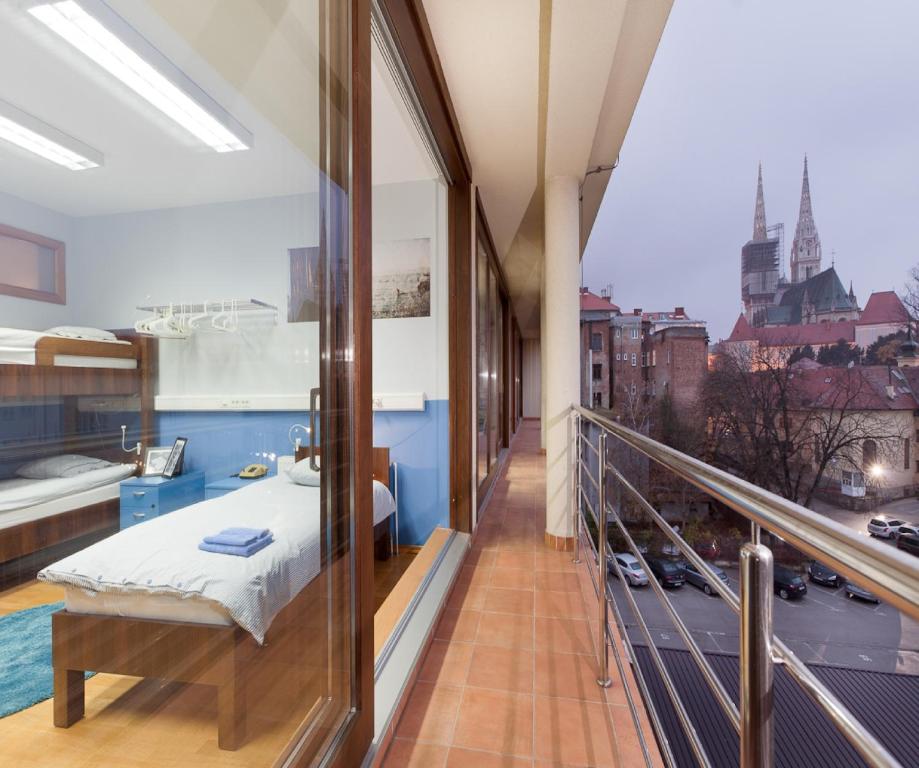 einen Balkon mit einem Bett und Stadtblick in der Unterkunft Hostel Bureau in Zagreb