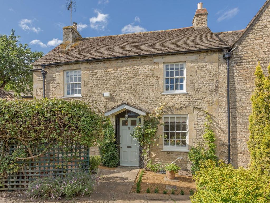 an old stone house with a white door at Middle Cottage in Easton on the Hill