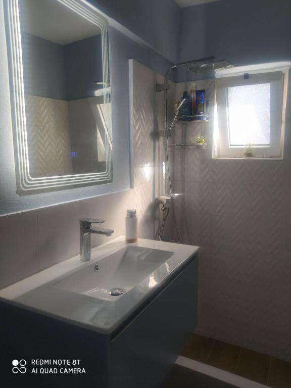 een badkamer met een witte wastafel en een spiegel bij Colorful House Tsoutsouras in Tsoútsouros