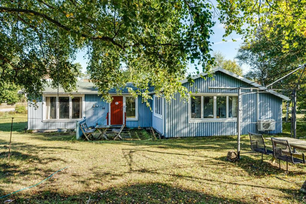 uma casa azul com uma porta vermelha debaixo de uma árvore em Nice holiday home near Skummelovs strand em Skummeslövsstrand