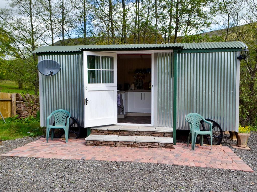 a green shed with two chairs in front of it at Mountain View in Llanthony