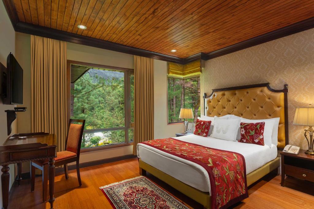 a bedroom with a bed and a desk and a window at Welcomhotel by ITC Hotels, Pine N Peak, Pahalgam in Pahalgām