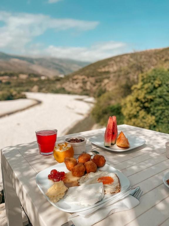 a table with plates of food on a table with a view at Guesthouse Lord Byron in Tepelenë