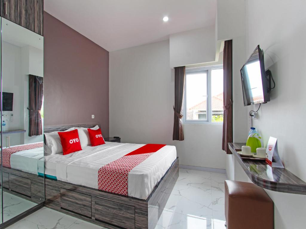 een slaapkamer met een bed met rode kussens en een televisie bij Super OYO Capital O 91665 D'prof Exclusive Guesthouse in Semarang