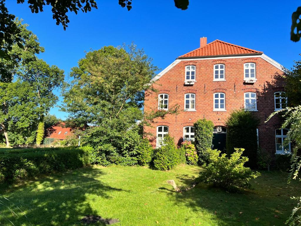 ノルデンにあるHistorischer Bauernhofの庭付きの大きな赤レンガ造りの家