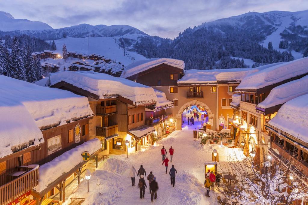 a group of people walking through a town covered in snow at Hôtel du Bourg in Valmorel