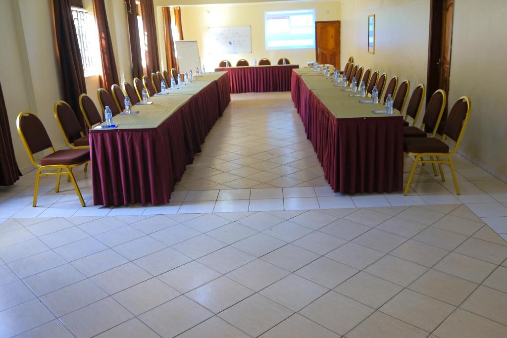 Acacia Hotel Mbarara في Mbarara: صف من الطاولات الطويلة في غرفة مع الكراسي