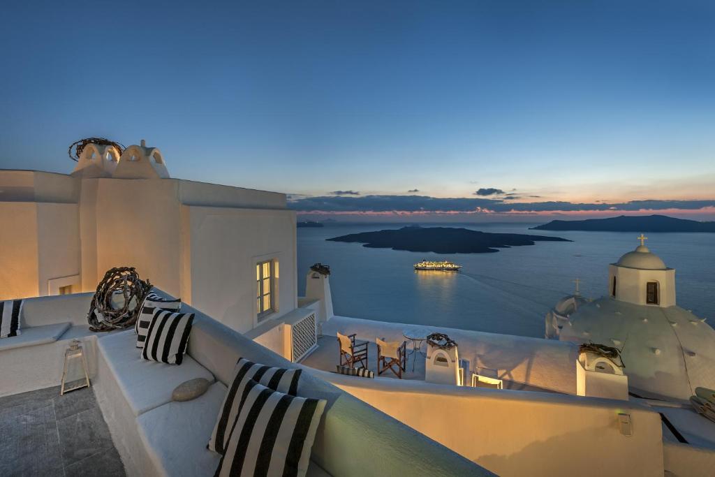 einen Balkon mit Blick auf das Meer bei Sonnenuntergang in der Unterkunft Aigialos Luxury Traditional Settlement in Fira