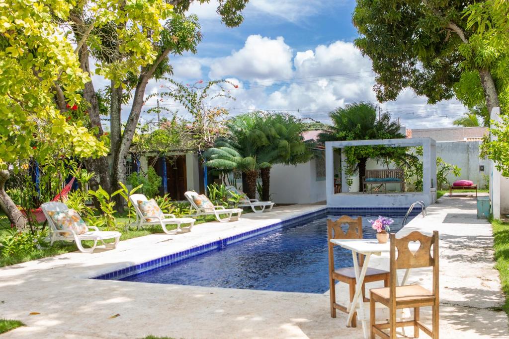 帕里普埃拉的住宿－Villa Ostello Pousada，后院设有带椅子和桌子的游泳池