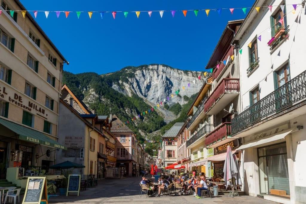 a group of people sitting in a street with a mountain at Coquet T1 hyper centre in Le Bourg-dʼOisans