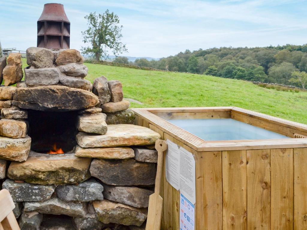 a hot tub in a stone wall with a fireplace at The Old Back Kitchen At Bonfield Ghyll Farm in Chop Gate