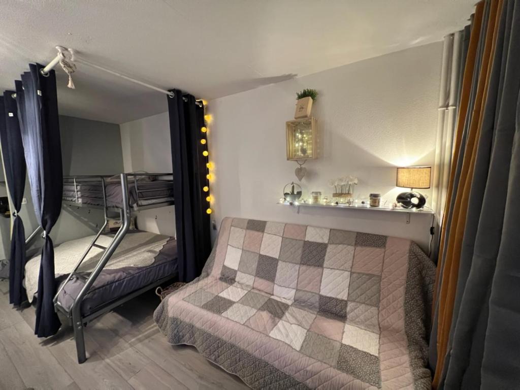 ein Schlafzimmer mit einem Bett und einem Etagenbett mit einer Leiter in der Unterkunft Coquet et accueillant Studio montagne la Mongie in Bagnères-de-Bigorre