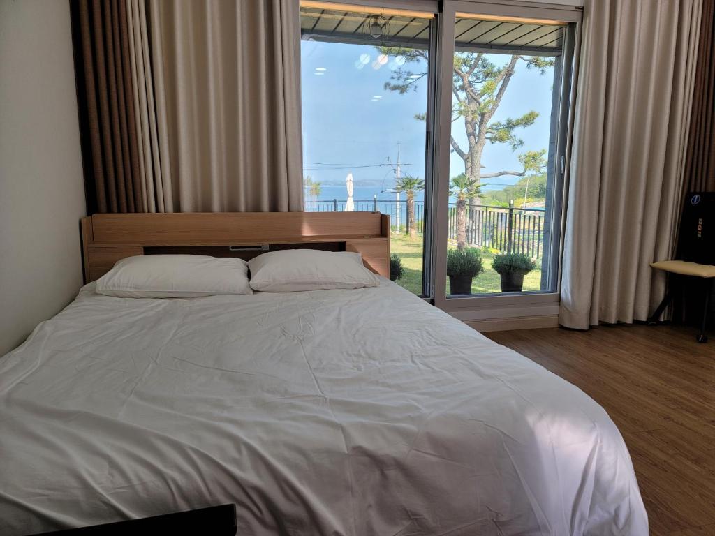 a bedroom with a large bed and a large window at Secret Garden Pension in Yeosu