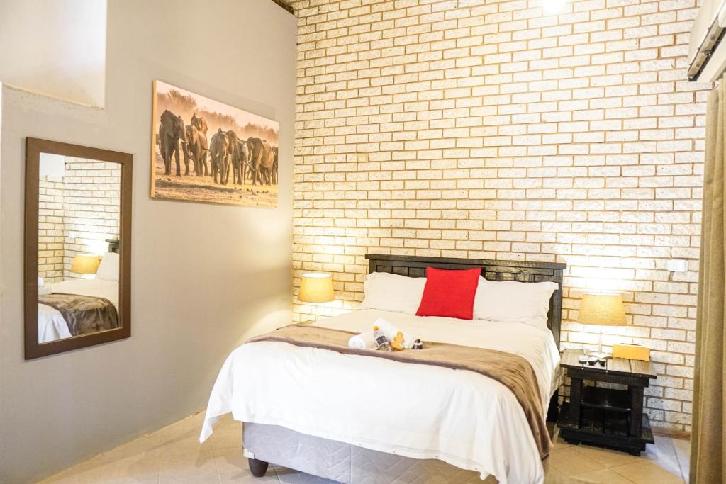 a bedroom with a brick wall and a bed at Lion's Guesthouse and The Buck&Lion Restaurant in Groblersdal