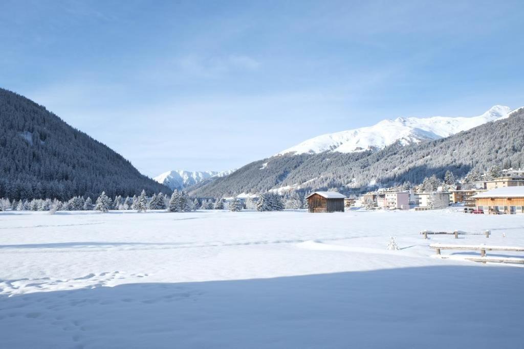 un campo innevato con una città e montagne di U Köhler a Davos