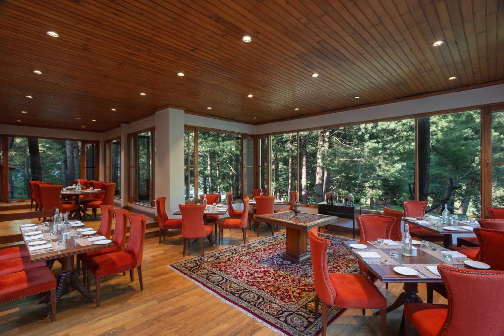 a restaurant with tables and chairs and windows at Welcomhotel by ITC Hotels, Pine N Peak, Pahalgam in Pahalgām