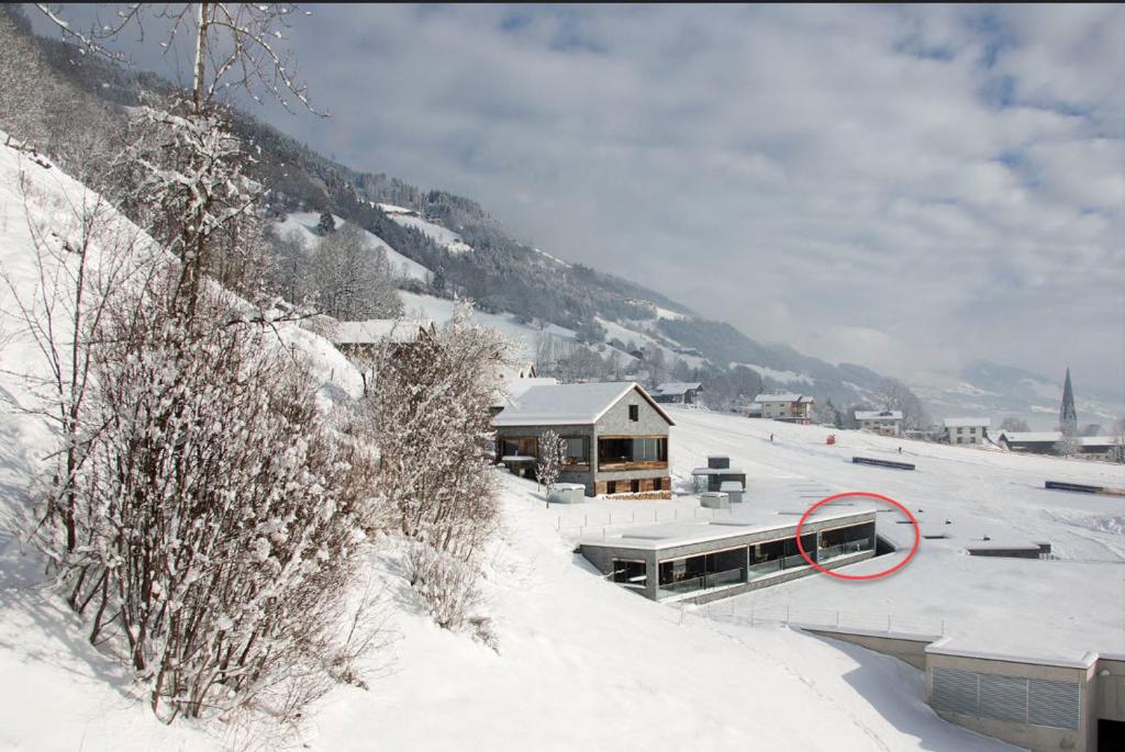 a house in the snow with a red circle on it at Smaragdresort in Bramberg am Wildkogel