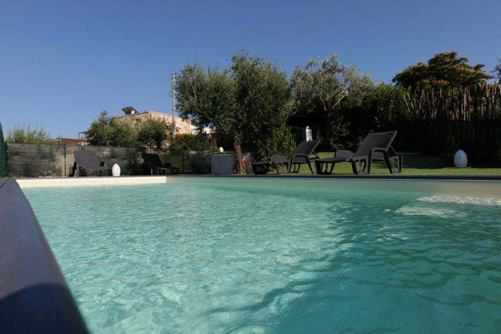 een zwembad met enkele stoelen en wat water bij Il Borgo Delle Querce Villa Fichi Piscina privata in Martina Franca