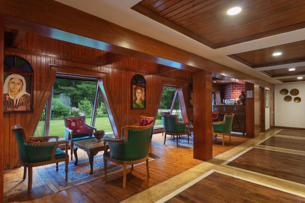 a dining room with wooden walls and green chairs at Welcomhotel by ITC Hotels, Pine N Peak, Pahalgam in Pahalgām