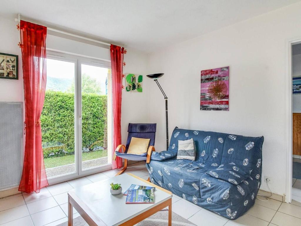 Una sala de estar con un sofá azul y una mesa. en T3 calme 6 pers, terrasse, jardinet, proche commodités - FR-1-402-24, en Esquièze - Sère