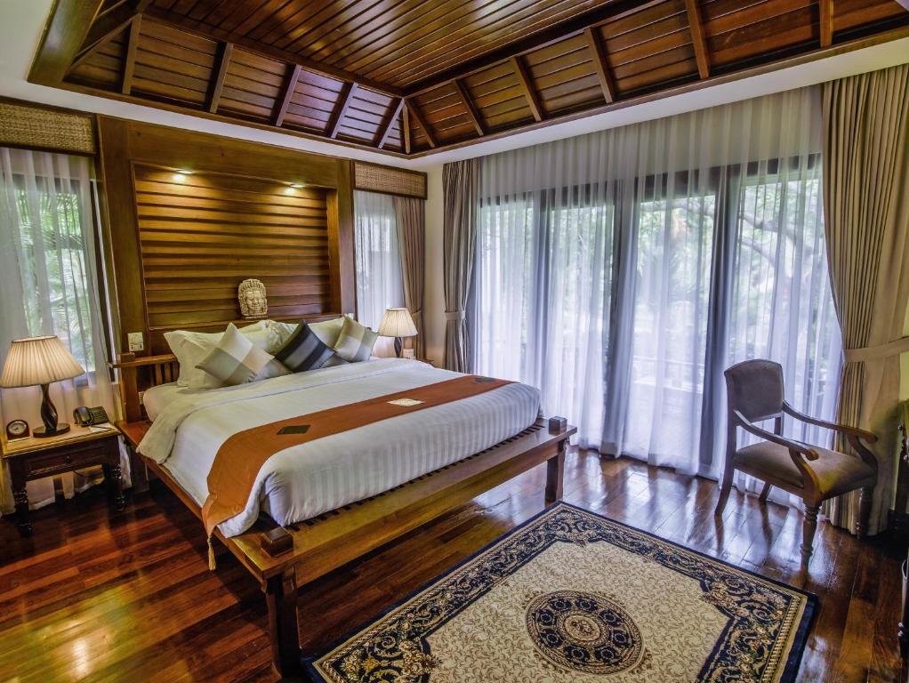 a bedroom with a large bed in a room with windows at Palace Residence & Villa Siem Reap in Siem Reap