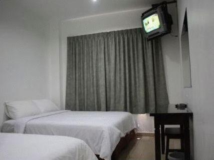 a hotel room with two beds and a television at Dynasty Inn - Wakaf Che Yeh in Wakaf Che Yeh