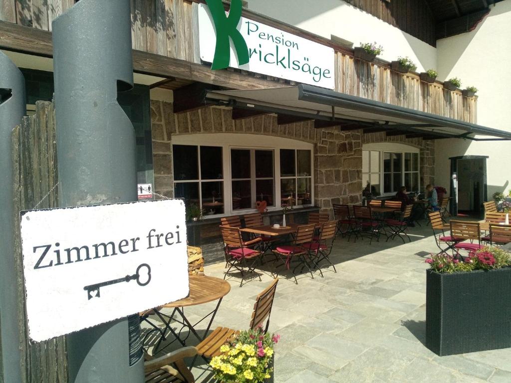 un restaurante con mesas y sillas y un cartel en un poste en Pension Kricklsäge en Philippsreut