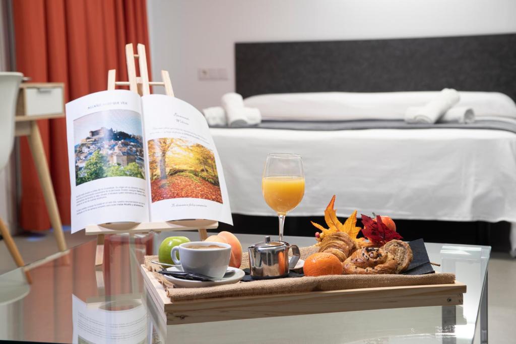 una bandeja de comida y un libro sobre una mesa en una habitación de hotel en Epsilon Alcañiz Hotel, en Alcañiz
