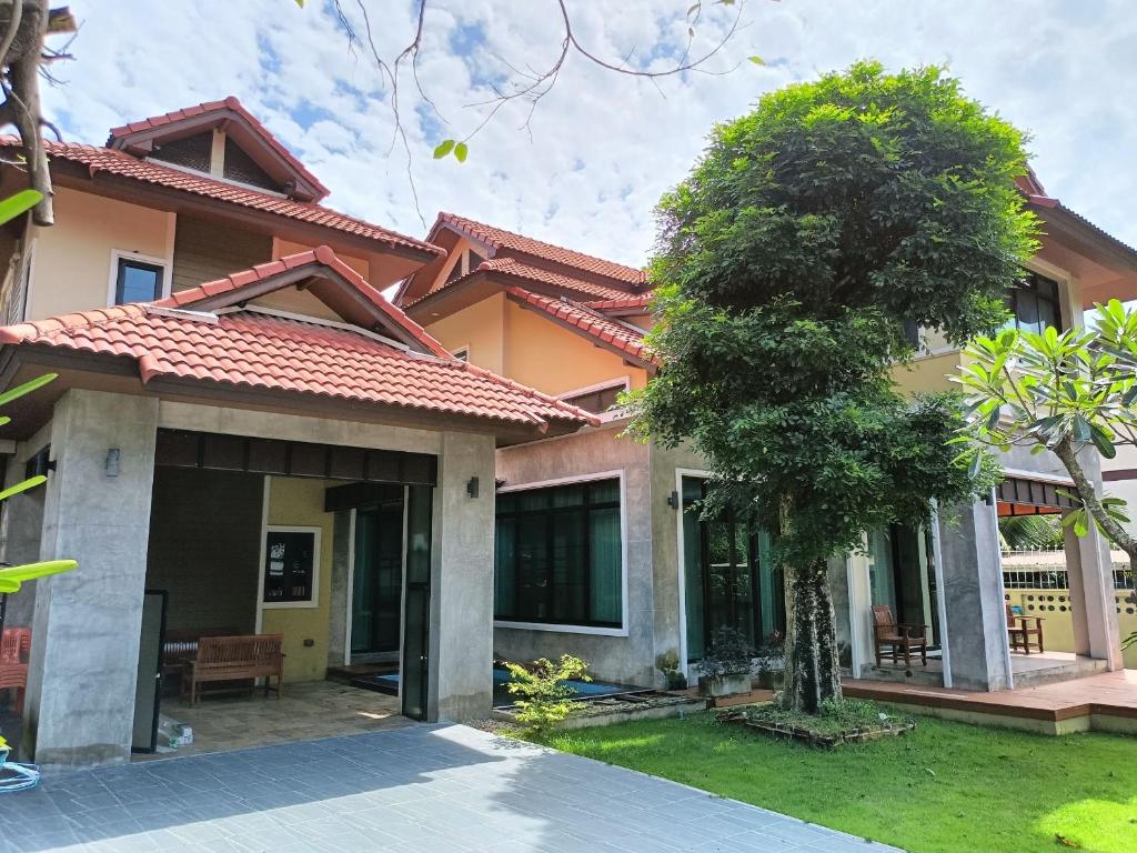 a house with a tree in front of it at Preme House Boutique in San Sai