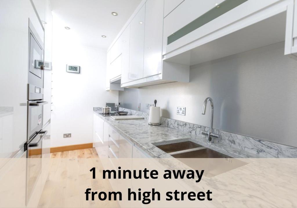 a kitchen with white cabinets and marble counter tops at 17 Rodney Road - Luxury Apartments in Cheltenham