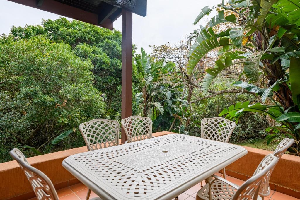 uma mesa branca e cadeiras numa varanda com árvores em San Lameer Villa 3116 - 3 Bedroom Standard - 6 pax - San Lameer Rental Agency em Southbroom