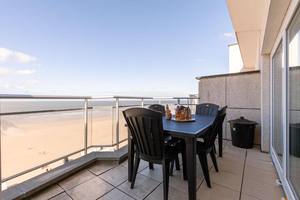 a table and chairs on a balcony with a view of the beach at Magnificent Apartment with Great Panoramic Seaview in De Haan