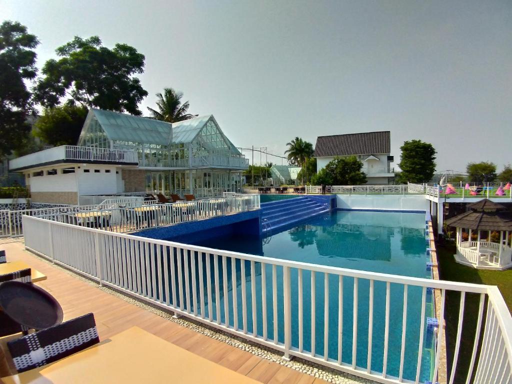 a swimming pool with a white railing next to a building at Chevilly Resort & Camp in Bogor