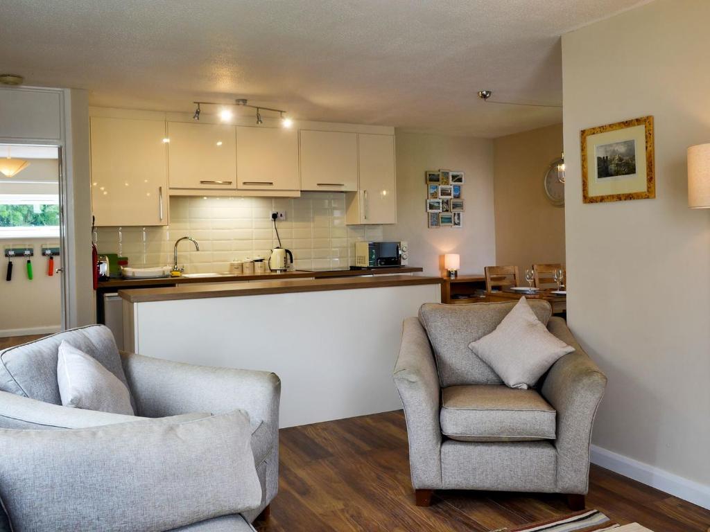 a living room with two chairs and a kitchen at Marina Apartment in Y Felinheli