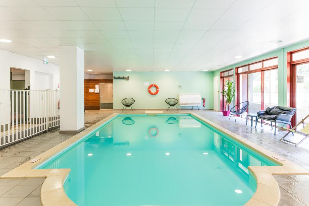 a large swimming pool with blue water in a building at Cerise Carcassonne Sud in Carcassonne