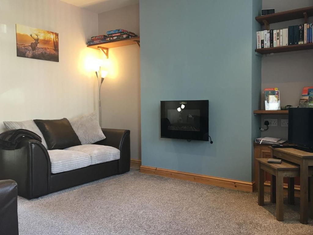 a living room with a couch and a flat screen tv at Nidd Cottage in Pateley Bridge