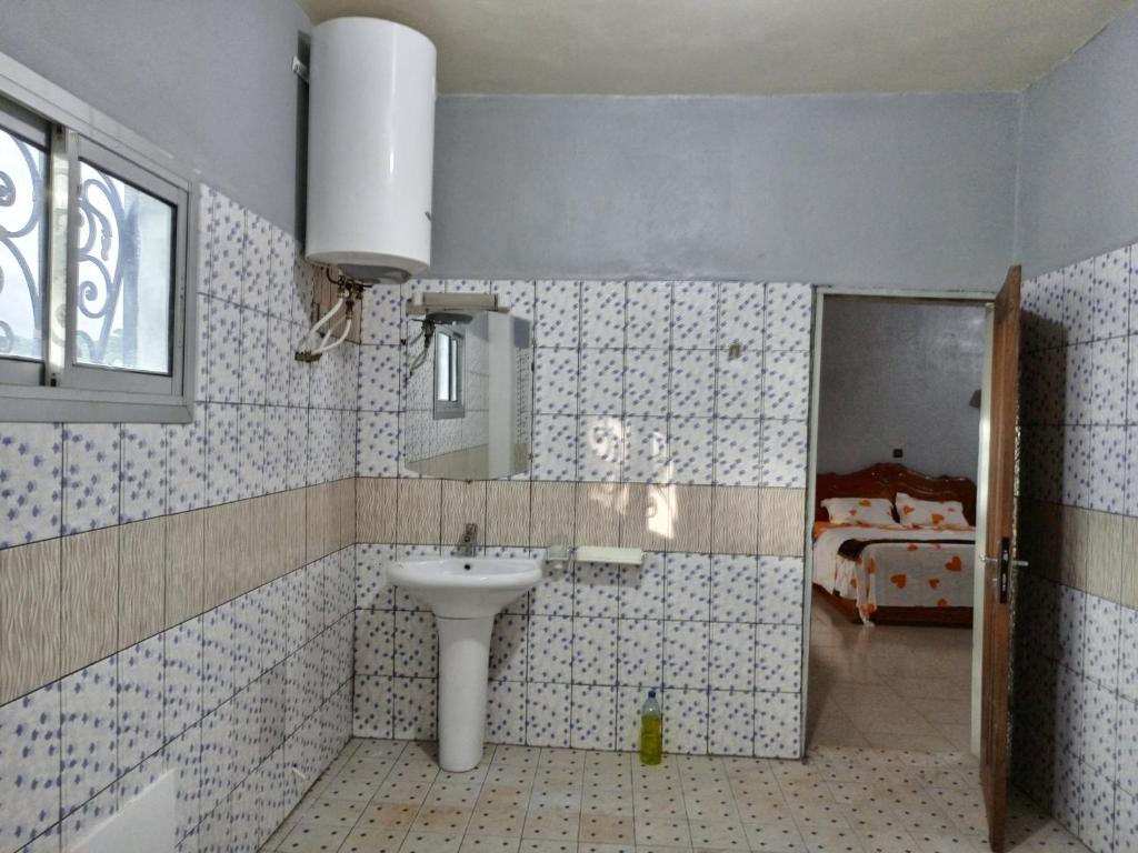 a bathroom with a sink and a mirror and a bed at RESIDENCE DU PELERIN - Villa l'écrin de verdure à Bandjoun in Bandjoun
