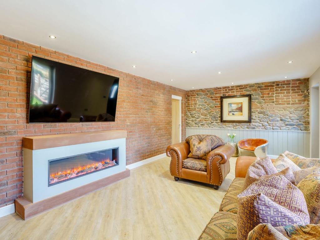 a living room with a fireplace and a tv on a brick wall at The Barnacle Goose - Uk35261 in Bowness-on-Solway