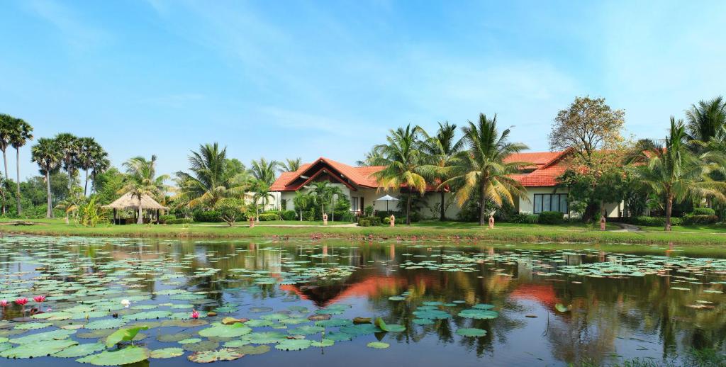 a house in front of a large pond with lilies at Palace Residence & Villa Siem Reap in Siem Reap